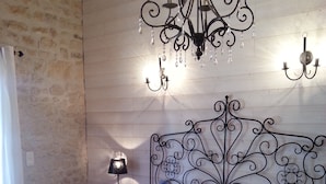 Un dormitorio con una colcha de estampado floral, un cabecero metálico decorativo y una araña.