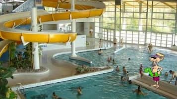 Une piscine intérieure à plusieurs niveaux, dotée de toboggans et entourée de murs en verre.