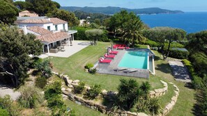 A residential property with a swimming pool, outdoor seating, and a view of the sea.