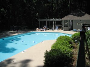 Una piscina con sillones de descanso y una pérgola.