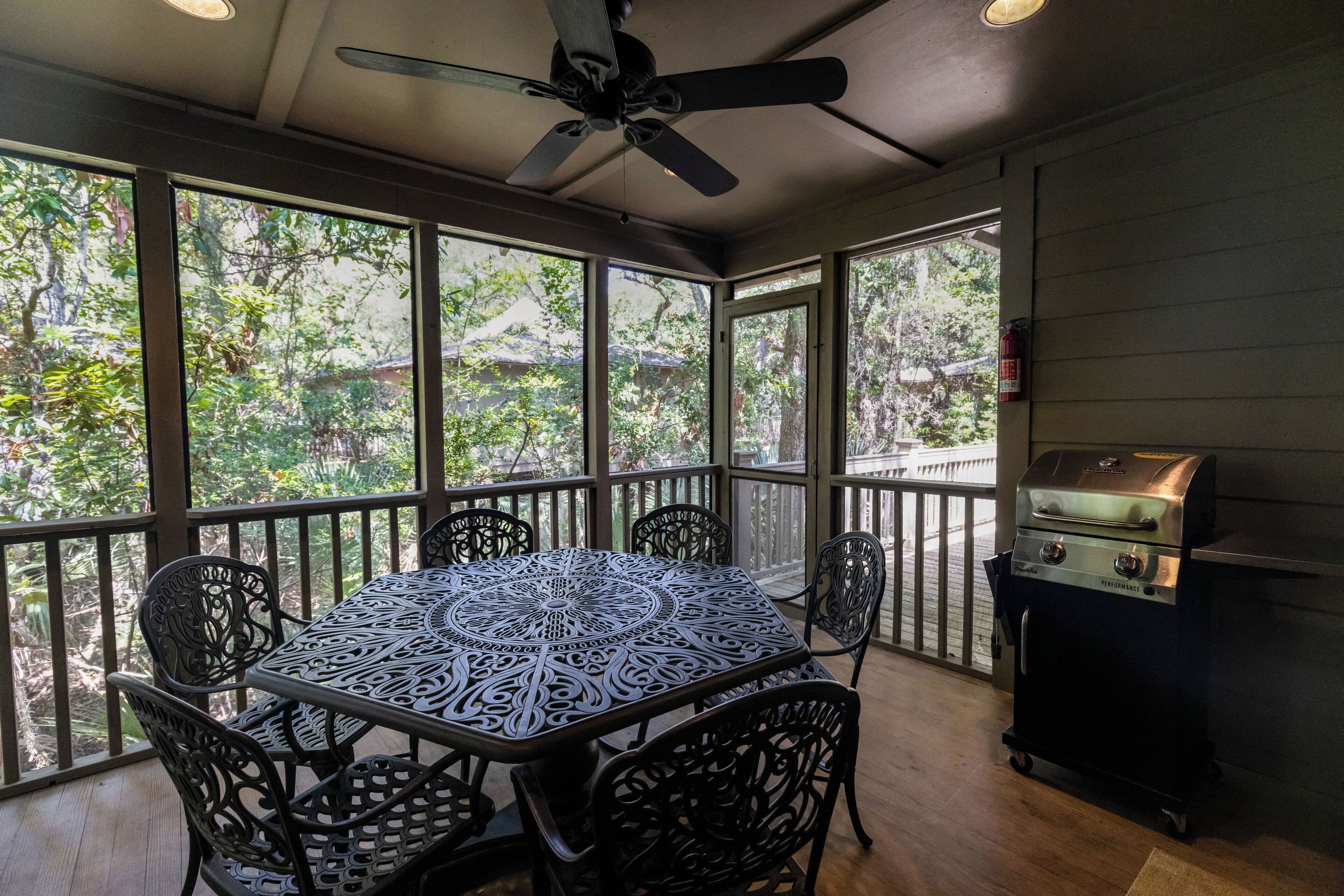 Eine überdachte Terrasse mit Tisch, Stühlen, Deckenventilator und Grill.