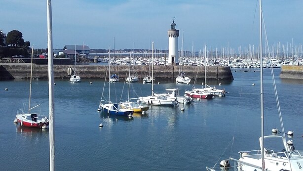 A marina with multiple boats docked, a lighthouse in the background, and a clear sky. - Apartment in quiet residence facing the beach with sea view (Quiberon)