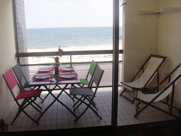 A balcony with a table set for two, overlooking a beach. - Apartment in quiet residence facing the beach with sea view (Quiberon)