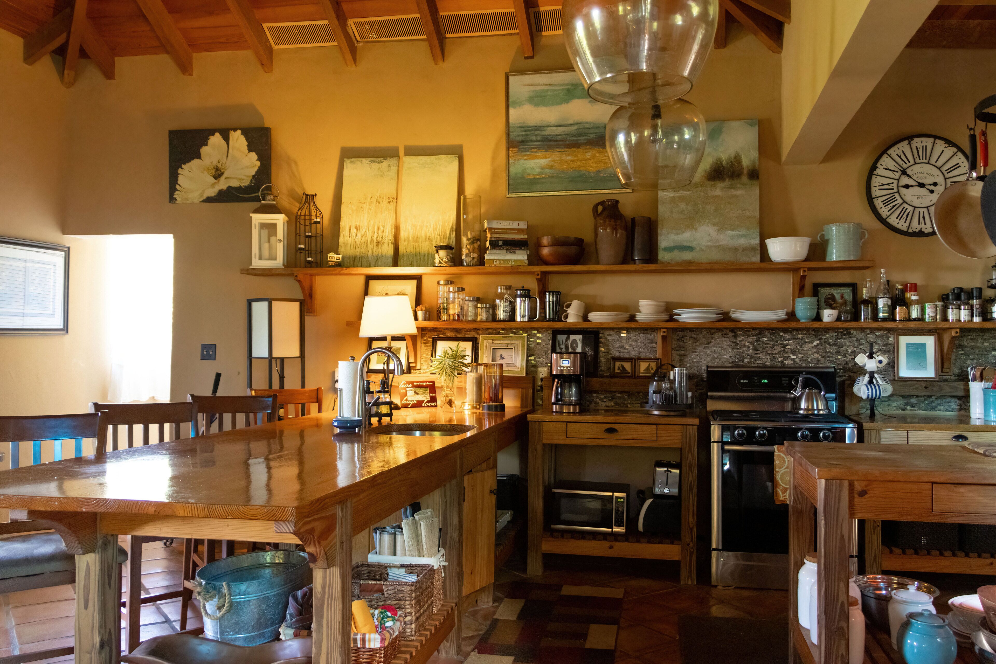 A cozy kitchen with wooden furniture, a large wooden table, and various kitchen appliances.