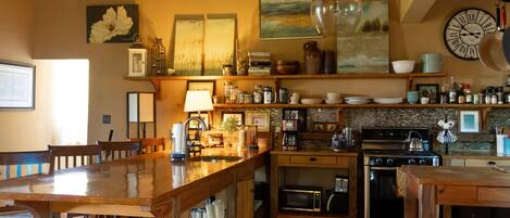 A cozy kitchen with wooden furniture, a large wooden table, and various kitchen appliances.