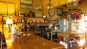 A kitchen with wooden countertops, a central island, stainless steel appliances, and various kitchen utensils.