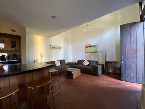 Um espaço de estar moderno com cozinha, sofá, mesa de centro e balcão de refeições com banquetas.