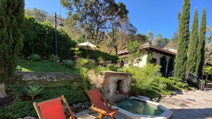 A courtyard with a small pool, red lounge chairs, and a stone pathway. - Cozy Studio In Quiet Condo With Heated Pool (Antigua Guatemala)