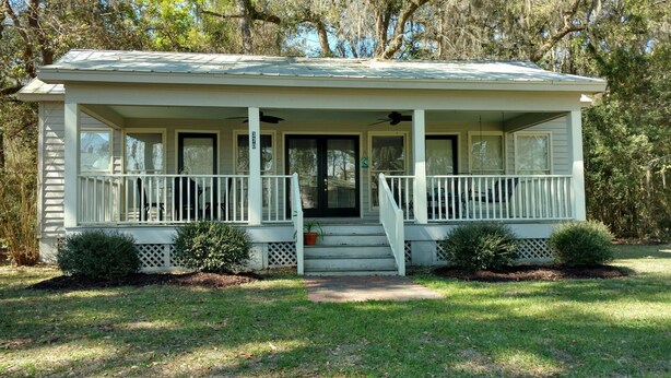 A single-story house with a front porch, a front door, and a small front yard. - Marsh-view Cottage in the Woods: surrounded by majestic oaks, birdsong & marsh! (Ridgeland)