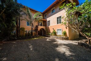 Un bâtiment à deux étages doté d’une cour intérieure, de murs en pierre et de plantes tropicales.