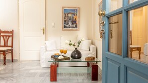 Een woonkamer met een glazen salontafel, een witte bank en een schilderij aan de muur.