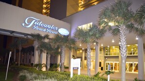 Exterior del Tidewater Beach Resort, con palmeras y una entrada bien iluminada.