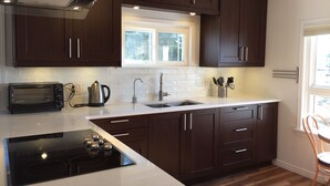 A modern kitchen with dark wooden cabinets, a built-in stove, a microwave, and a window above the sink.