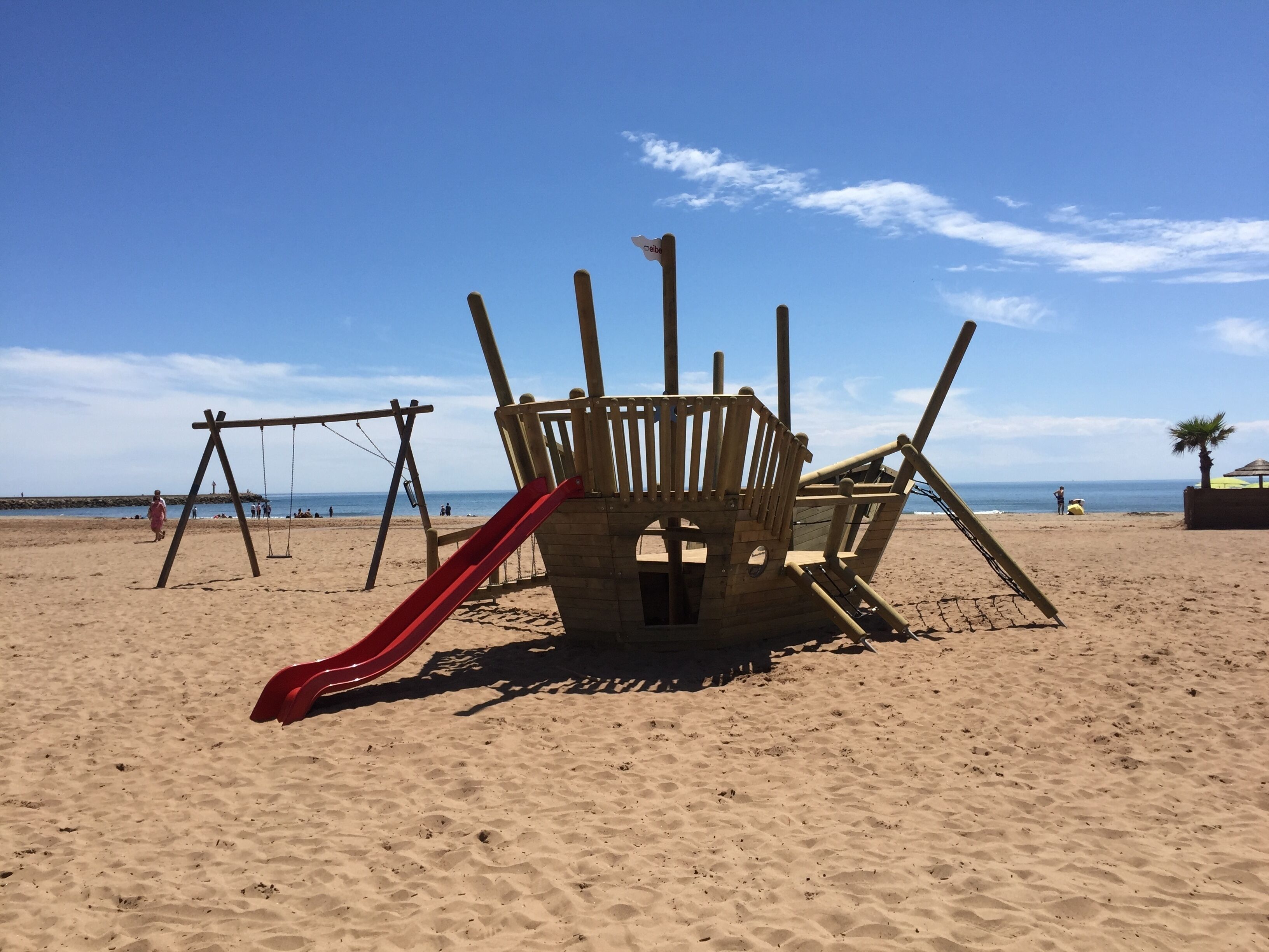 A beach play area with a slide and swings.