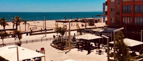 Een gebied aan het strand met terras, palmbomen en een gebouw met de tekst
