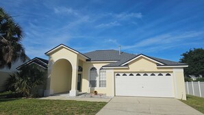 A single-story house with a garage, a small porch, and a clear blue sky. - 4BR Pool & Spa Home, Sleeps 8 – Near Disney, Clermont FL (Clermont)