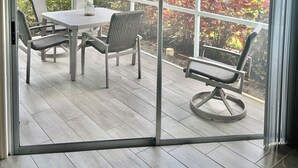 Ein Zimmer mit einer Glasschiebetür, die auf eine Terrasse mit Tisch und Stühlen führt.