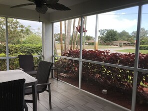 Enjoy dining or socializing in this covered outdoor space with a table and two chairs, surrounded by views of the surrounding landscape.