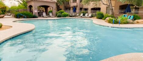 Una piscina con sillas de descanso y un pabellón.