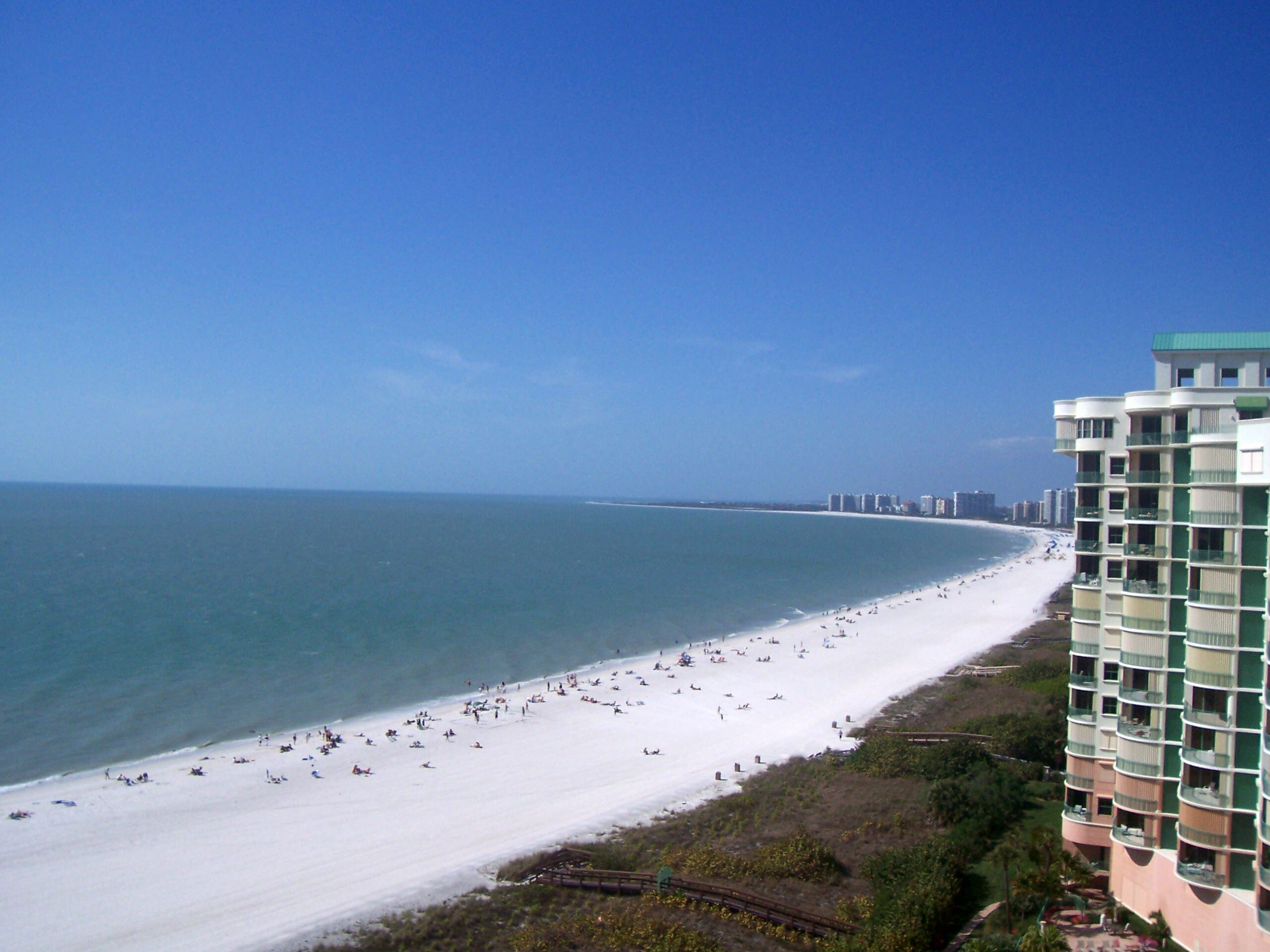 Uma praia com um edifício grande ao lado.