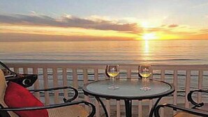 Una mesa con dos copas de vino y una vista del atardecer sobre el océano.