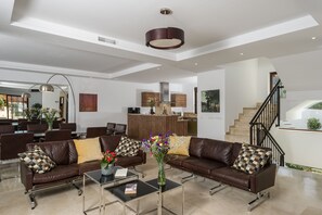 A spacious living area with leather sofas, a coffee table, and a vase of flowers.