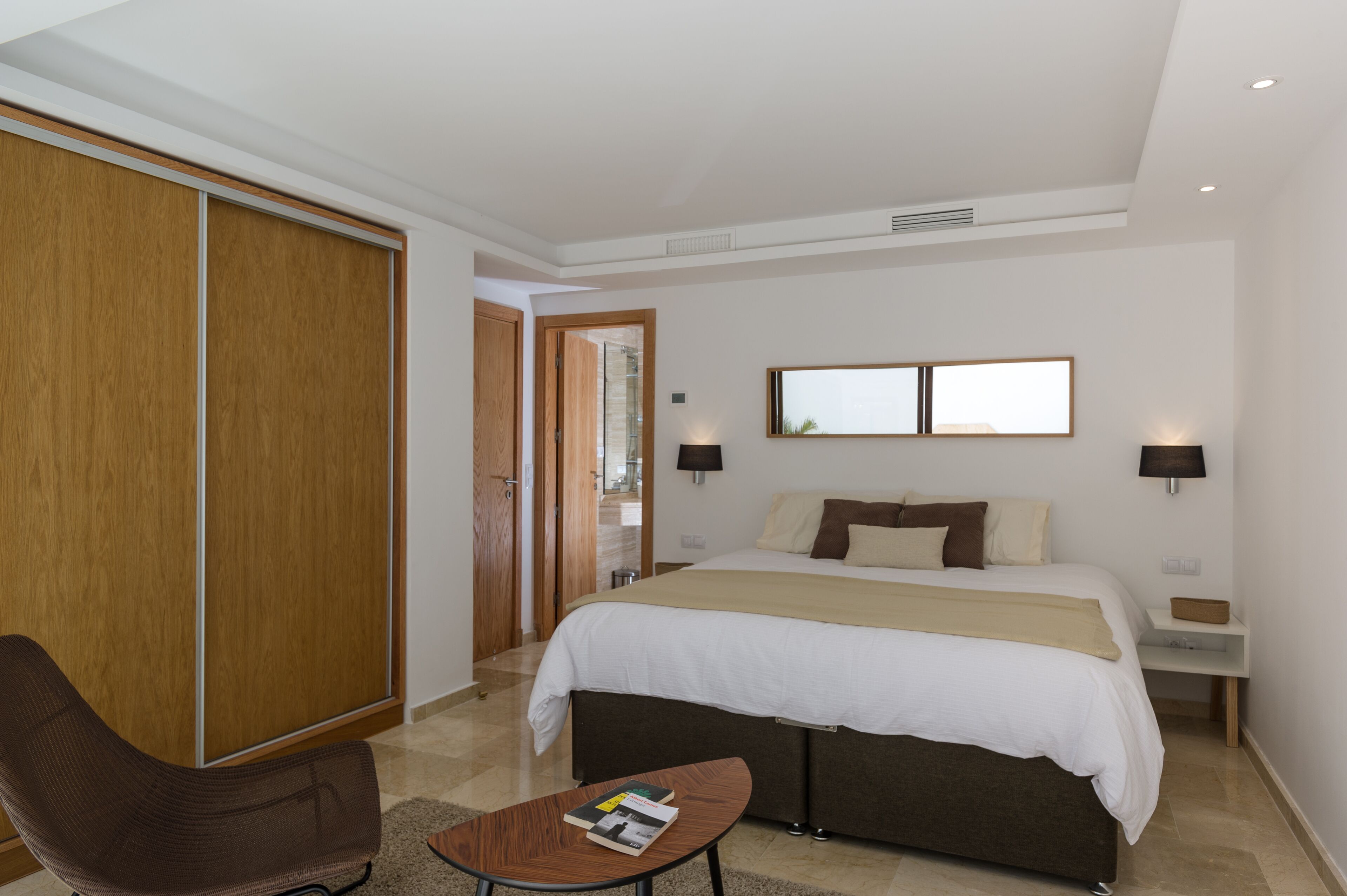 Une chambre d’hôtel comprenant un lit, des tables de chevet, une chaise, une petite table et une armoire.