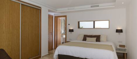 Une chambre d’hôtel comprenant un lit, des tables de chevet, une chaise, une petite table et une armoire.