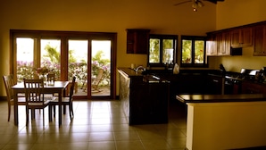 A kitchen with a dining area, large windows, and a ceiling fan. - Relaxing Beach House Just Steps from Nicaragua's Best Surf Breaks (San Diego)