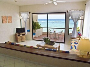 Enjoy ocean views from the balcony with a table and chairs, featuring a TV and a plant.