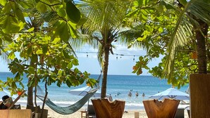 Ein Strand mit Hängematten, Holzpflanzgefäßen und Blick auf den Ozean.