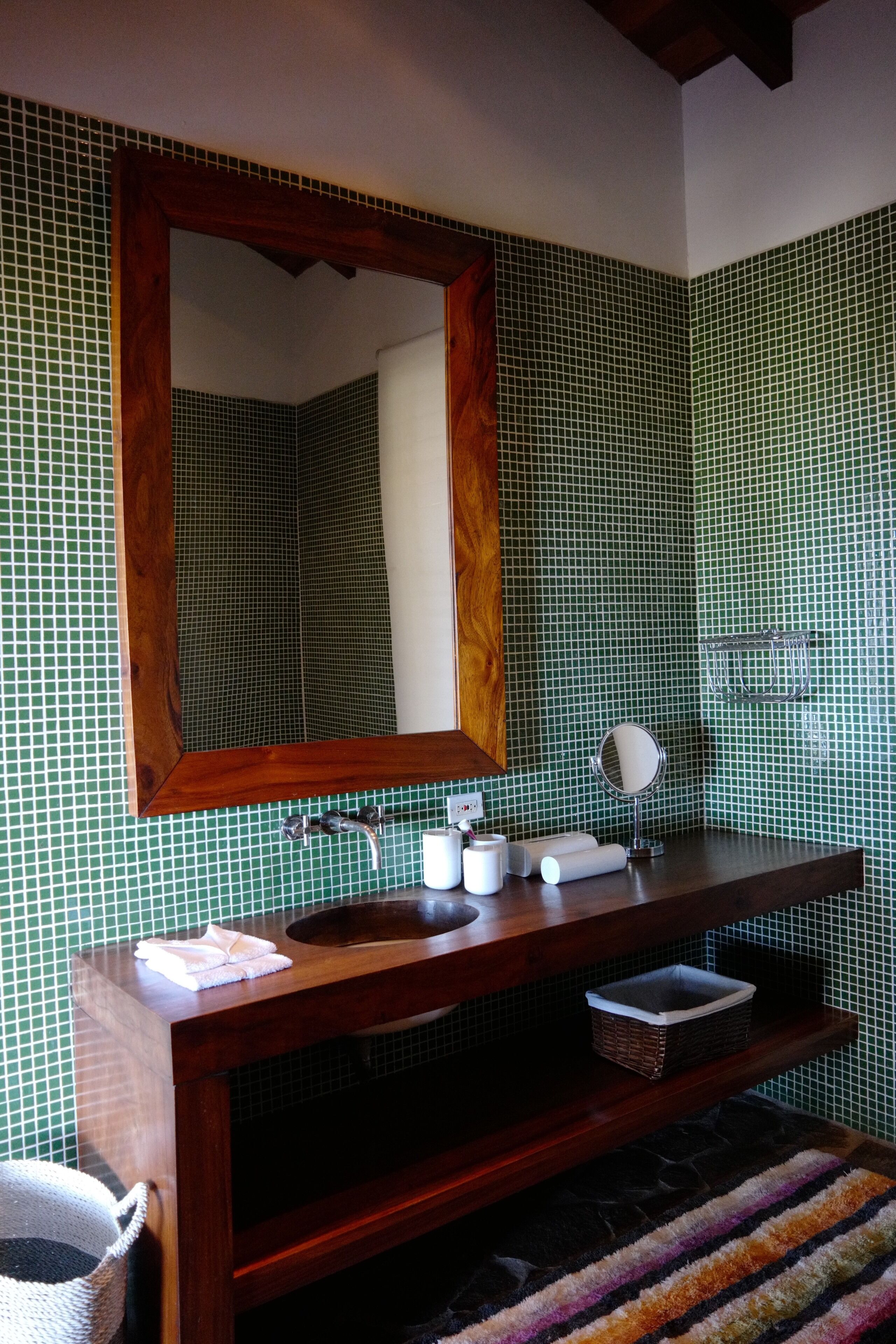 A bathroom with a wooden vanity, a sink, a mirror, and a tiled backsplash.