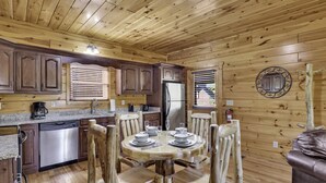 Un interior de madera con cocina, mesa de comedor, sillas y refrigerador.