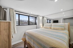 Quarto com cama, janela, televisão e guarda-roupa de madeira.