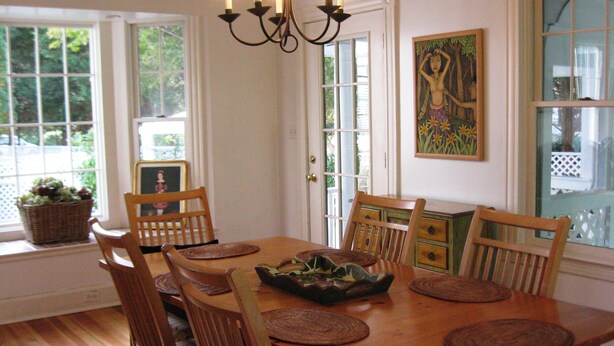 A dining area with a wooden table, chairs, woven placemats, and a chandelier. - Autumn House Shoreby Hill Jamestown Village  Pool, 5 Bdrms, Central Air, Office (Jamestown)