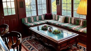A cozy room with a large window seat, a glass-top coffee table, and a patterned rug. - Autumn House Shoreby Hill Jamestown Village  Pool, 5 Bdrms, Central Air, Office (Jamestown)
