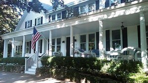 A two-story house with a porch, a flag, and a stone wall. - Autumn House Shoreby Hill Jamestown Village  Pool, 5 Bdrms, Central Air, Office (Jamestown)