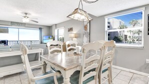 Un espace repas comprenant une table et des chaises, un ventilateur de plafond et une vue sur l’extérieur.