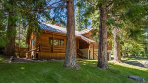 Une cabane en rondins, avec une façade en bois, un porche et un escalier menant à l’entrée.
