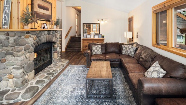 Un salon chaleureux avec une cheminée en pierre, un canapé en cuir marron et une table basse en bois.