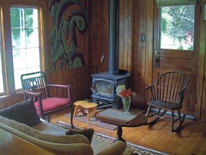 Cozy cabin-style seating area with a wood-burning stove, comfortable sofa, and two rocking chairs.