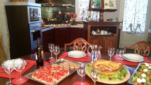 A dining table set with plates, glasses, and a variety of dishes including pizza, salad, and a large grilled dish.