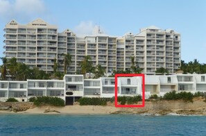 Un hôtel situé en bord de mer, doté de nombreux balcons, offrant un accès direct à la plage et une vue sur l’océan.