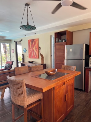 A kitchen with a central island, wooden chairs, a ceiling fan, and a refrigerator.