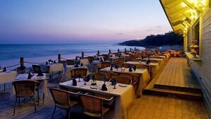 An outdoor dining area with tables and chairs, overlooking a beach at dusk. - Luxury villa V2, sleeps 6, Elevator to the beach, Cliff, Pine Cliffs Golf (Olhos de Agua)