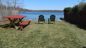 A picnic setup with a red table and two green chairs facing a lake.