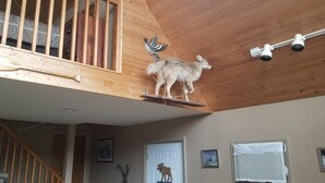 A loft-style room with a wooden ceiling, a wooden bat, a mounted owl, and a mounted deer.