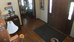 A room with a wooden floor, a door with a glass panel, a desk with a lamp, and a chair.
