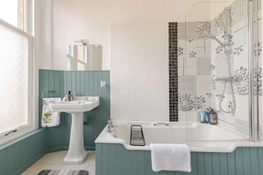 Een bad/douchecombinatie, een haardroger, handdoeken