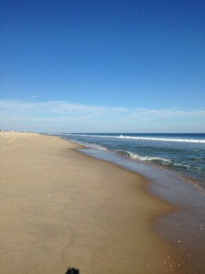 A wide sandy beach with gentle waves and a clear blue sky.